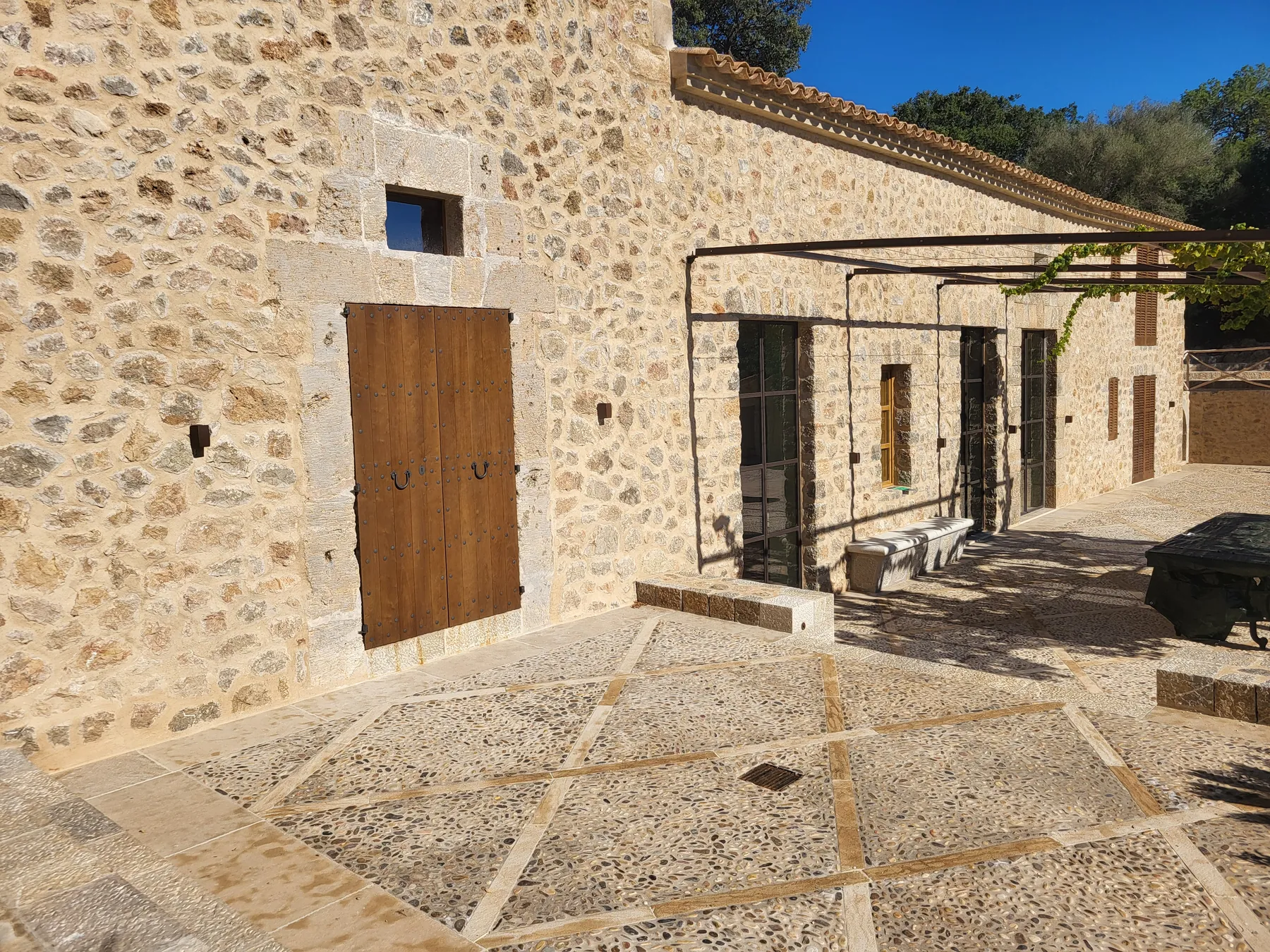 Fachada de piedra vista y pérgola de una vivienda rehabilitada en Esporles, Mallorca.